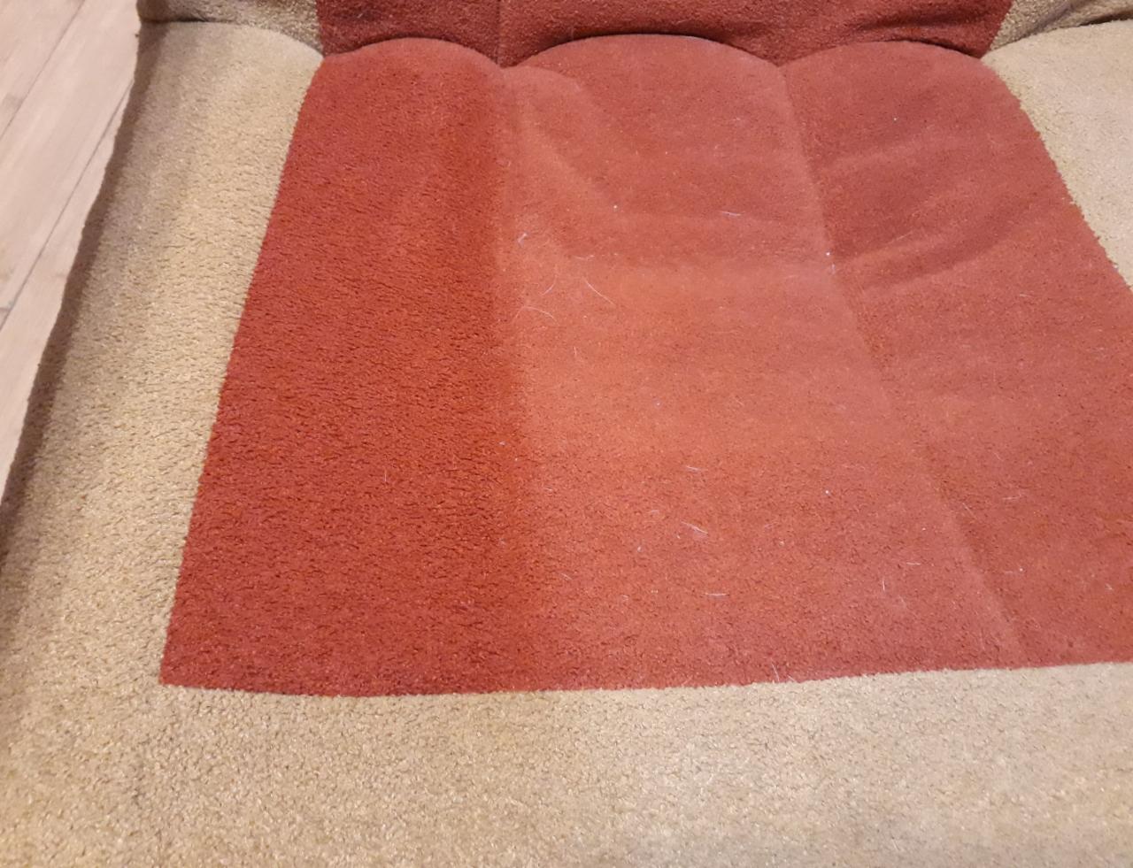 Fragment kanapy z widoczną różnicą w kolorze i czystości po wypraniu części tapicerki w odcieniach brązu i beżu.