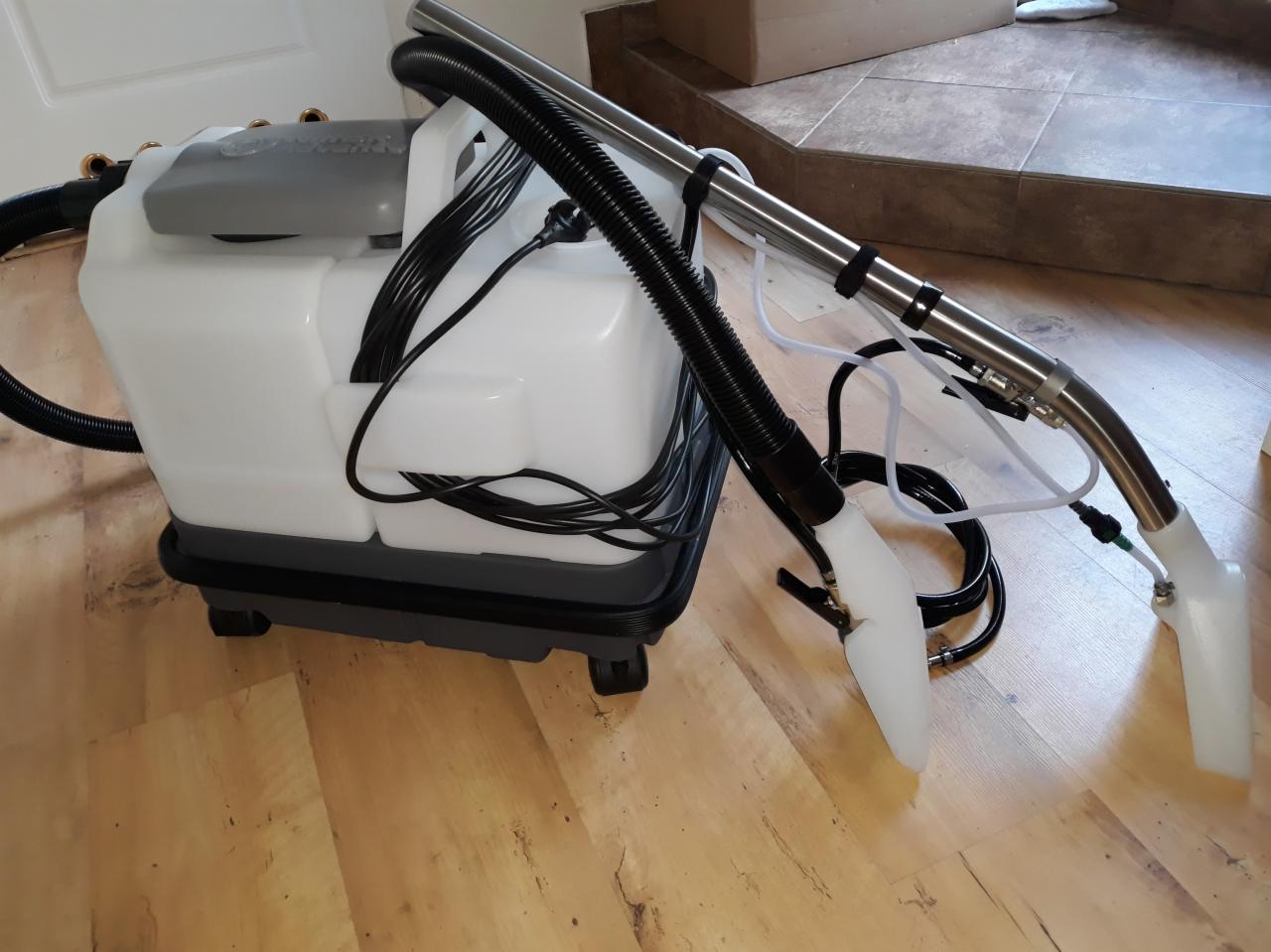 Profesjonalny odkurzacz piorący z metalową lancą i plastikową ssawką na drewnianej podłodze, gotowy do użycia.