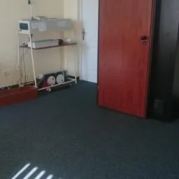 Gabinet w Gdyni z biurkiem, krzesłem i aparaturą na półkach, przygotowany do konsultacji.