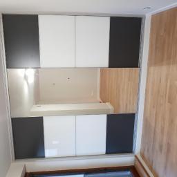 Eurodis Sp.zoo - Duża szafa przesuwna z lustrzanymi drzwiami, panelami białymi i grafitowymi, odbijająca fragment pokoju z drewnianą podłogą.