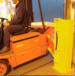 Operator wózka widłowego Linde, w ciemnym ubraniu i brązowych butach, siedzi na pomarańczowym wózku, który zbliża się do żółtej bramy przemysłowej z czarnym uchwytem. W tle widoczna niebieska ściana.