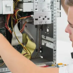 Technik w Radomiu diagnozuje problem z otwartą obudową komputera stacjonarnego, widoczne kable i płyta główna.