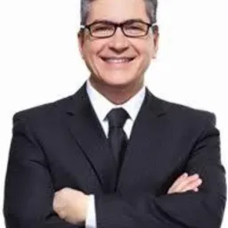 Uśmiechnięty mężczyzna w okularach i garniturze z czarnym krawatem, skrzyżowanymi rękami na białym tle. Portret biznesowy.