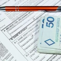 Wypełniony formularz PIT-11, długopis i stos banknotów 50 zł w Radkowie. Dokumenty przygotowane do rozliczenia podatkowego.