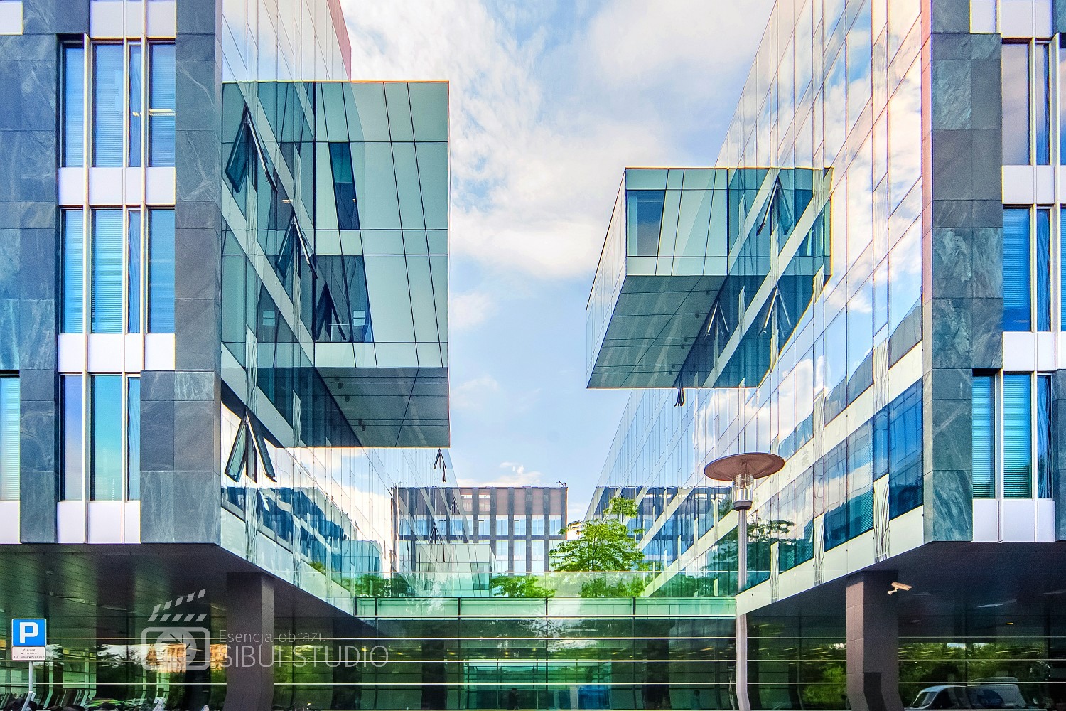 Nowoczesna architektura biurowa z przeszklonymi fasadami i wystającymi elementami, widziana z dołu w słoneczny dzień.