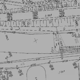 Fragment mapy geodezyjnej z naniesionymi numerami działek, oznaczeniami granic i elementami infrastruktury, w skali szarości.