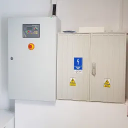 Szafa sterownicza firmy Himonsa oraz skrzynka z wyłącznikiem prądu zlokalizowane w Ostrołęce, z naklejkami ostrzegawczymi o napięciu elektrycznym.