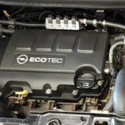 Silnik Opel ECOTEC z instalacją LPG, widoczne wtryskiwacze gazu, akumulator i inne elementy osprzętu w samochodzie serwisowanym w Policach.