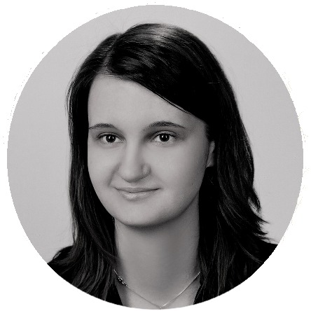 Portret kobiety z ciemnymi włosami, uśmiechającej się delikatnie, w czarno-białej tonacji, na jasnoszarym tle w okrągłej ramce.