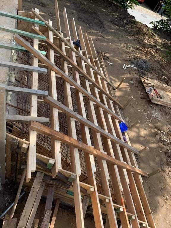 Konstrukcja szalunkowa z drewnianych belek i siatki zbrojeniowej, przygotowana do wylania betonu na zboczu.