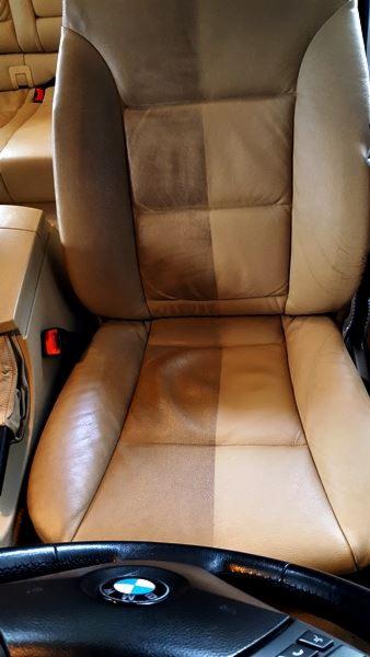 Skórzany fotel samochodowy BMW, w połowie wyczyszczony, ukazujący różnicę w kolorze i czystości przed i po zabiegu, widoczna kierownica.