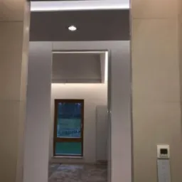 Nowoczesne wykończenie wnętrza z podświetlanym sufitem i ścianami wyłożonymi płytami, widok na pokój z oknem