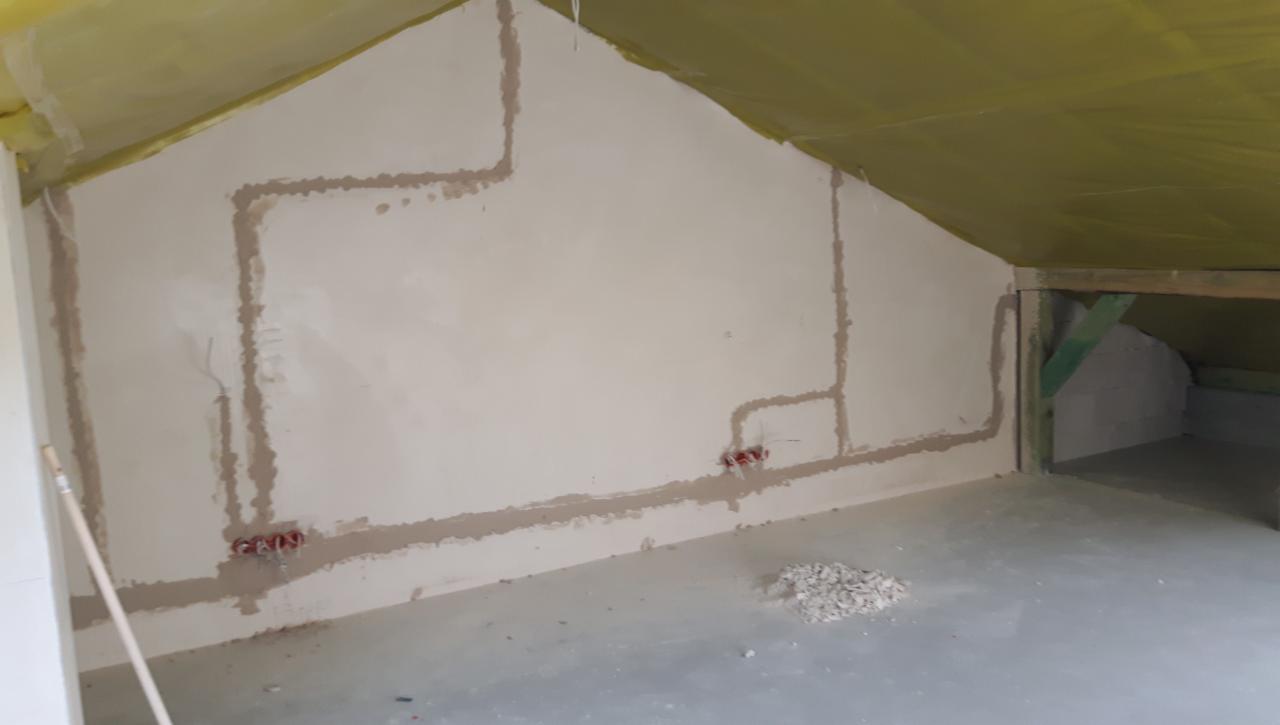 Wewnętrzne okablowanie elektryczne w nowo budowanym poddaszu, z widocznymi puszkami instalacyjnymi i bruzdami wypełnionymi gipsem, przygotowane do dalszych prac wykończeniowych.