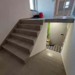 Schody wykończone płytkami w nowoczesnym domu z widocznym wejściem do pomieszczenia z dekoracyjną ścianą z mchu i wzorzystą podłogą.