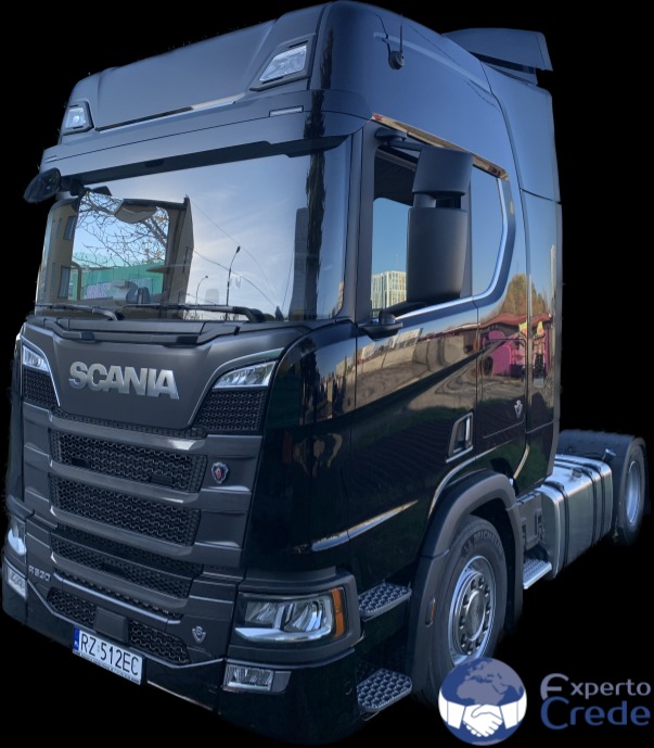 Czarny ciągnik siodłowy marki Scania R330 z widoczną tablicą rejestracyjną, sfotografowany w plenerze z niskiej perspektywy.