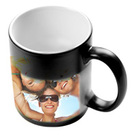 Czarny kubek z białym wnętrzem, na którym nadrukowane jest zdjęcie uśmiechniętych osób w okularach przeciwsłonecznych, widoczne odbitki i fotogadżety.