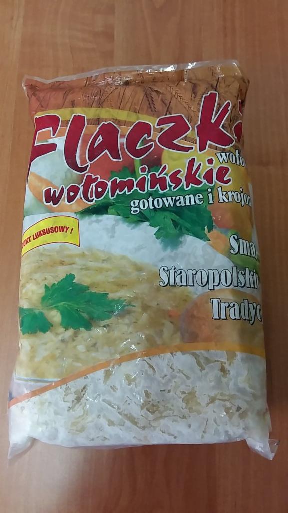 Foliowe opakowanie flaczków wołomińskich, gotowanych i krojonych, z widoczną zawartością na drewnianym tle.