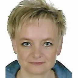 Portret kobiety o krótkich blond włosach i niebieskich oczach, ubrana w dżinsową koszulę, na białym tle.