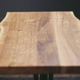 Blat drewniany z naturalną krawędzią, wykończony na gładko, wsparty na metalowych nogach, widoczny z perspektywy lekko z góry.