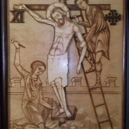 przedsiębiorca Oleksandr Hrabovskyy - Ręcznie wykonana płaskorzeźba przedstawiająca scenę ukrzyżowania, z postaciami i krzyżem wykonanymi w technice pirografii na jasnym drewnie, oprawiona w ciemną ramę.