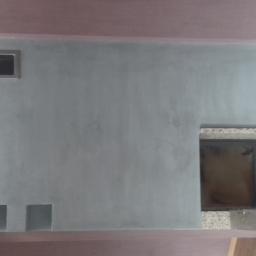 Jpp Painting&Decorating - Ściana po szpachlowaniu z otworem na kominek obudowanym płytkami i prostokątnym otworem wentylacyjnym powyżej, widoczne trzy małe kwadratowe wnęki u dołu.