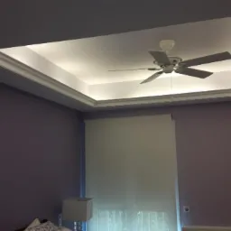 Podwieszany sufit z oświetleniem LED i wentylatorem w pokoju o fioletowych ścianach, widok na roletę okienną.