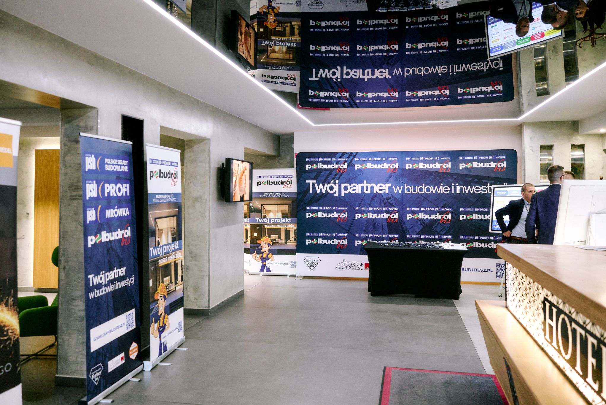 Wnętrze hotelu Europa podczas konferencji Polbudrol: roll-upy PSB Profi Mrówka, Polskie Składy Budowlane, banery z hasłem 'Twój partner w budowie i inwestycji'.