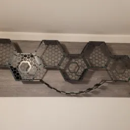 Nowoczesna, modułowa konstrukcja z metalu i drewna w kształcie plastra miodu, zamontowana na ścianie, pełniąca funkcję półek i przejść.