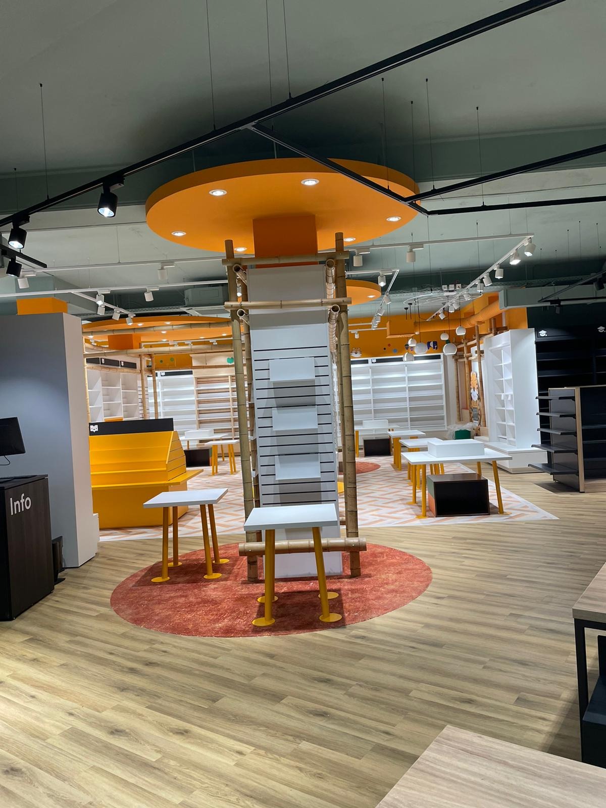 Wnętrze nowocześnie urządzonego sklepu z elementami bambusa i oświetleniem punktowym, widoczne regały i stoliki ekspozycyjne na drewnianej podłodze.