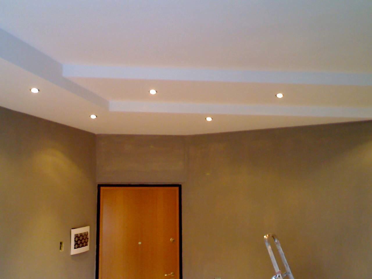 Pomieszczenie po malowaniu ścian na odcienie brązu, z zamontowanymi punktowymi lampami w suficie podwieszanym i widocznymi drzwiami w ciemnej futrynie oraz fragmentem drabiny.