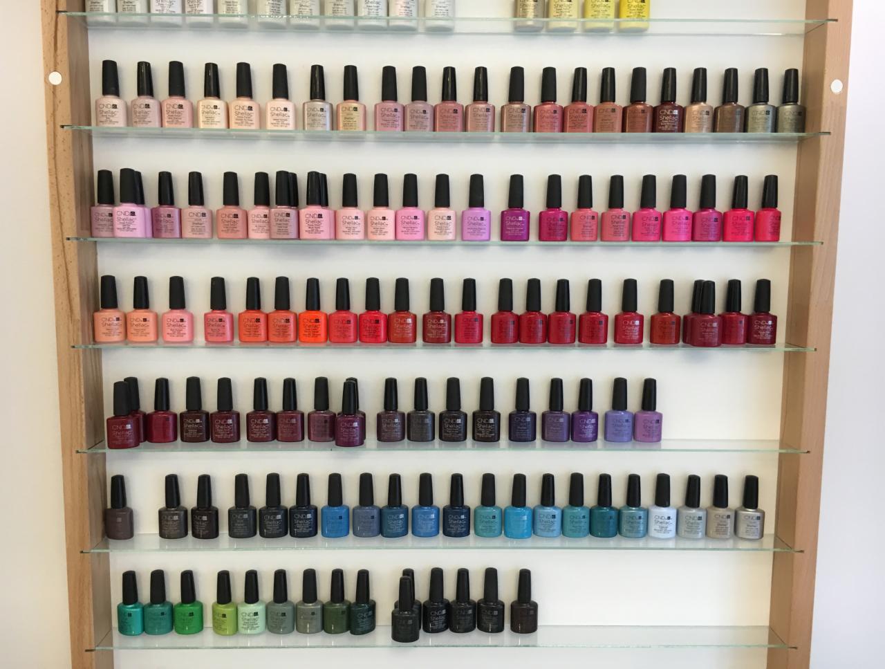 Półka z lakierami do paznokci CND Shellac w odcieniach różu, czerwieni, brązu, zieleni i błękitu, ułożonych kolorystycznie.