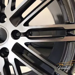 Błyszcząca, dwukolorowa felga aluminiowa z logo firmy w prawym dolnym rogu, prezentująca precyzyjne wykonanie i dbałość o detale.