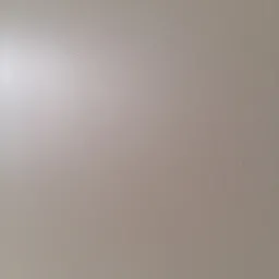 Jasna, gładka powierzchnia ściany z delikatną teksturą, oświetlona z lewej strony, tworząca subtelny gradient światła.