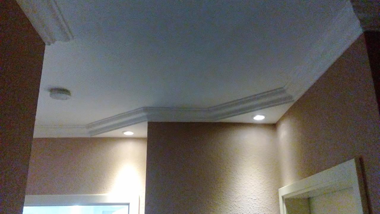 Fragment wnętrza po remoncie: pomalowany sufit z dekoracyjną sztukaterią i wbudowanymi punktami świetlnymi, ściany w odcieniach beżu z widoczną fakturą.