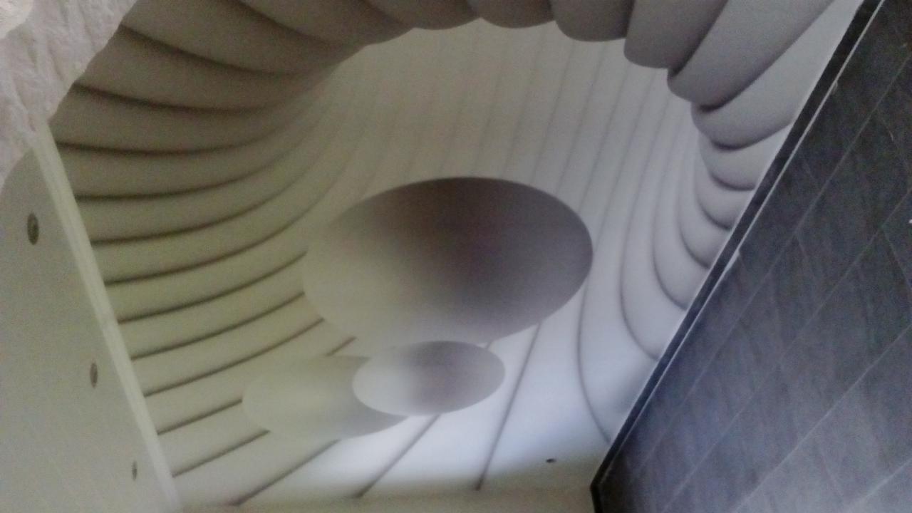 Nowoczesny sufit z dekoracyjną, trójwymiarową tapetą z motywem elips i wypukłych pasów, widziany pod kątem.