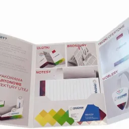 Rozłożona broszura reklamowa firmy poligraficznej prezentująca przykładowe realizacje: opakowania kartonowe z tektury litej, ulotki, broszury, notesy, teczki ofertowe, wobblery i zawieszki,...
