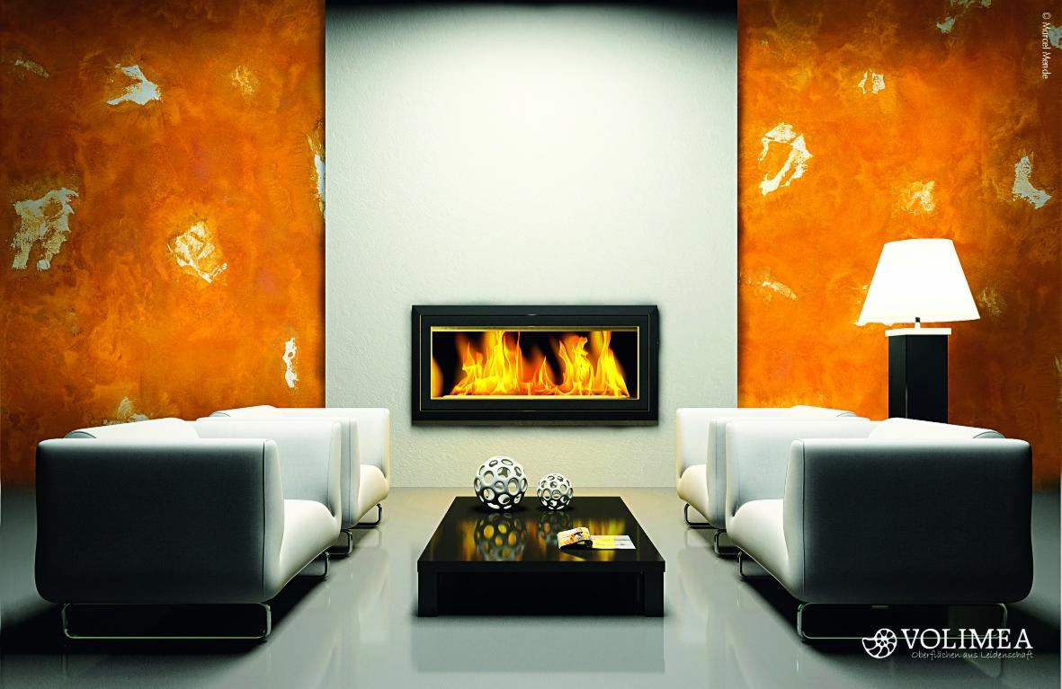 Nowoczesny salon z kominkiem wbudowanym w ścianę, pomarańczowe ściany boczne z dekoracyjną fakturą, białe sofy, czarny stolik kawowy z ażurowymi kulami dekoracyjnymi i lampa na czarnej podstawie.