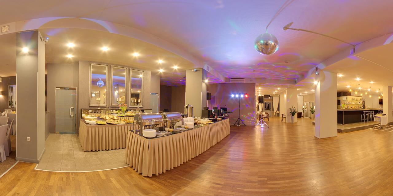 Panoramiczny widok sali bankietowej z parkietem, stołami bufetowymi z cateringiem, barem i kulą dyskotekową pod sufitem.