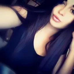 Portret młodej kobiety z długimi, ciemnymi włosami, wykonany w stylu selfie z lekkim uśmiechem.