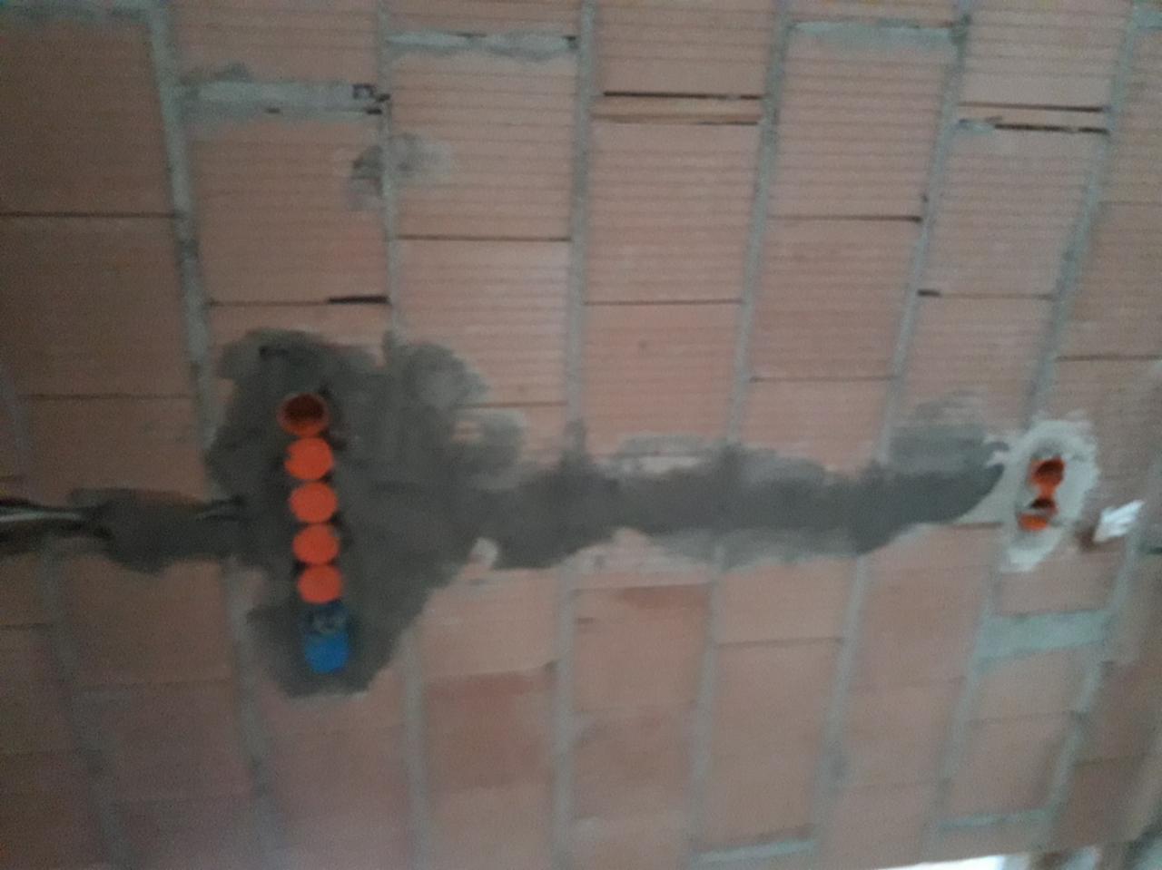 Montaż instalacji elektrycznej w stropie z cegły w Krzywaczce, widoczne pomarańczowe rury instalacyjne zalane zaprawą.