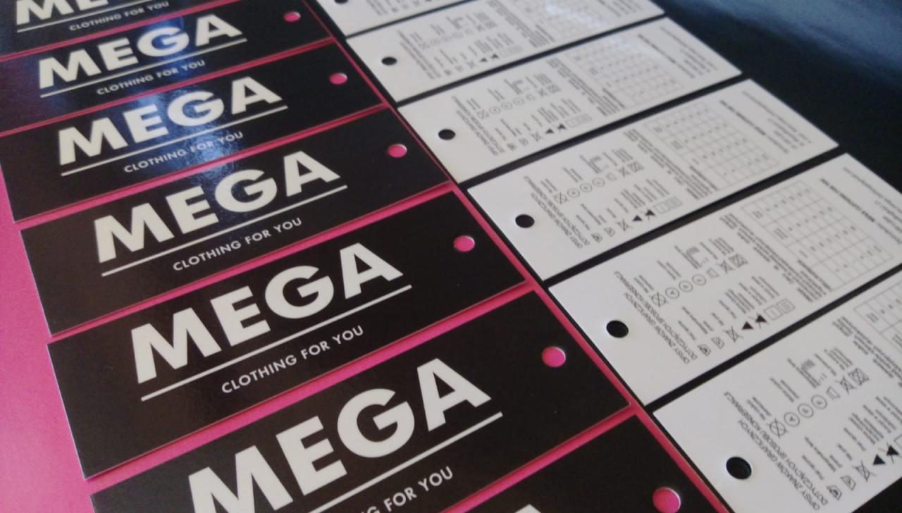 Partia czarno-białych etykiet odzieżowych z logo 'MEGA CLOTHING FOR YOU', część z instrukcjami prania, ułożonych rzędami na różowym podłożu.