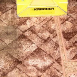 Czyszczenie brudnego dywanu w geometryczne wzory przy użyciu żółtego odkurzacza piorącego Karcher PW 20, widoczna różnica w kolorze po czyszczeniu.