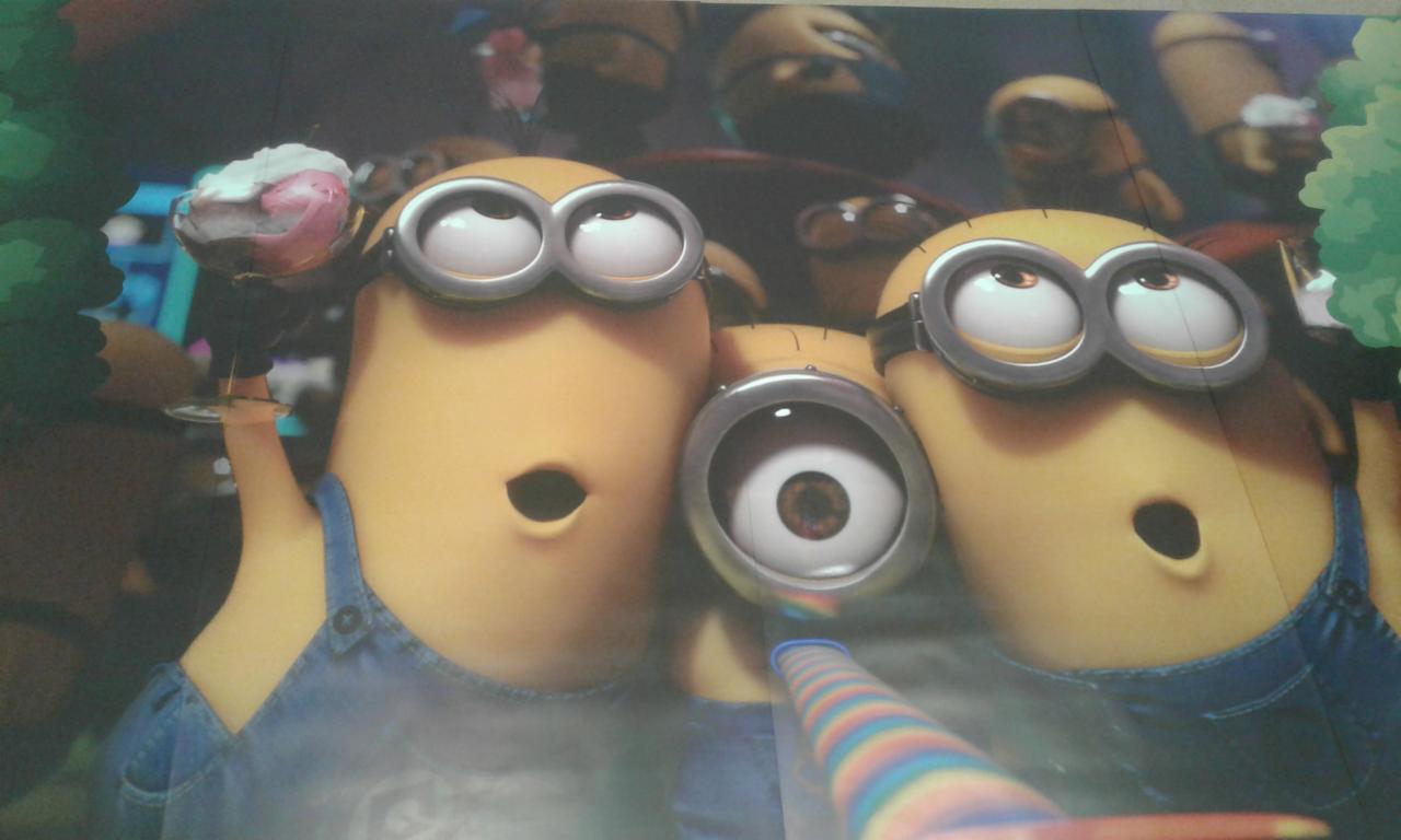 Ściana z fototapetą przedstawiającą postacie Minionków w Bardzlinie, jeden z nich trzyma deser lodowy, a drugi dmucha w serpentynę.