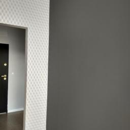 Glazurtech - Fragment korytarza z pomalowaną na szaro ścianą i ścianą przy wejściu do pokoju z białą tapetą w geometryczny wzór rombów.