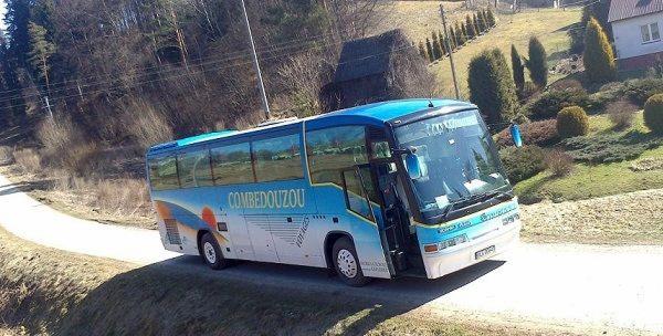 Autokar firmy transportowej z Olszanicy na wiejskiej drodze, z otwartymi drzwiami i widocznym logo 'Combedouzou'.
