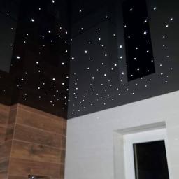 WilczykBud - Nowoczesna łazienka z podświetlanym sufitem imitującym gwiazdy, brązowe płytki imitujące drewno i białe płytki ścienne, widoczne okno.