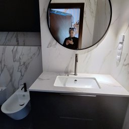 Maniak Design Anna Maniak - Nowoczesna łazienka z marmurowymi płytkami, okrągłym lustrem, czarną armaturą i bidetem, odbicie osoby robiącej zdjęcie w lustrze.