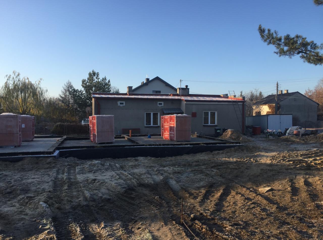 Wykop pod fundamenty domu z widocznymi bloczkami betonowymi i częściowo wylaną płytą fundamentową, przygotowany teren pod budowę.