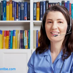 Uśmiechnięta kobieta z headsetem na tle regału z książkami w kolorowych okładkach.