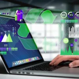 Laptop z nakładką graficzną prezentującą dane i symbol recyklingu, obsługiwany przez dłoń na klawiaturze.